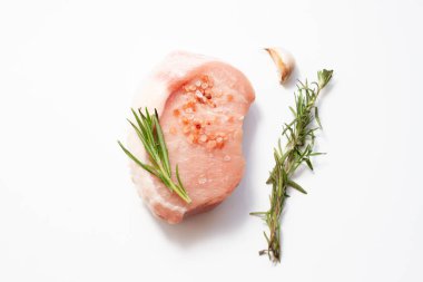 Sarımsaklı kırmızı domuz bifteği ve beyaz arka planda biberiye. Üst Manzara. Yumuşak Odaklanma