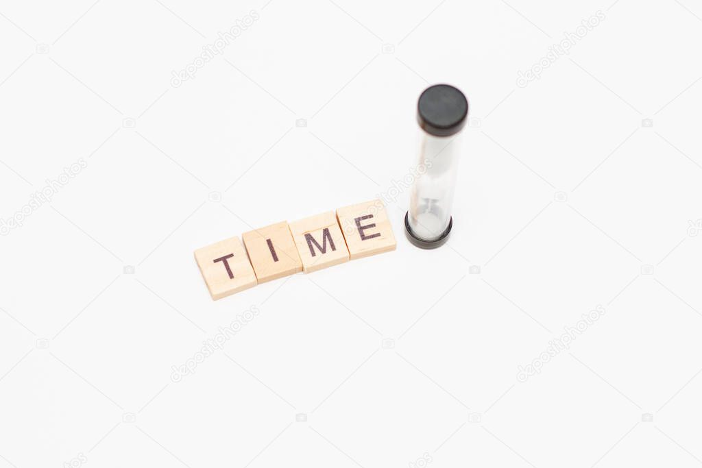 Time inscription made of wooden blocks and hourglass on a white background.