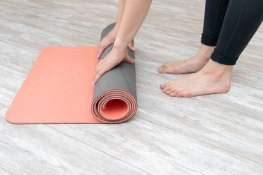 Evdeki ahşap zeminde yoga dersinden sonra paspası yuvarlanan bir kadın. Yoga yapan bir kız..