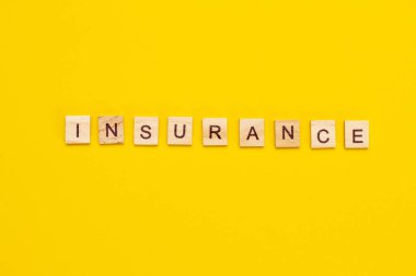 Sarı arkaplandaki tahta küplerden INSURANCE yazıtları