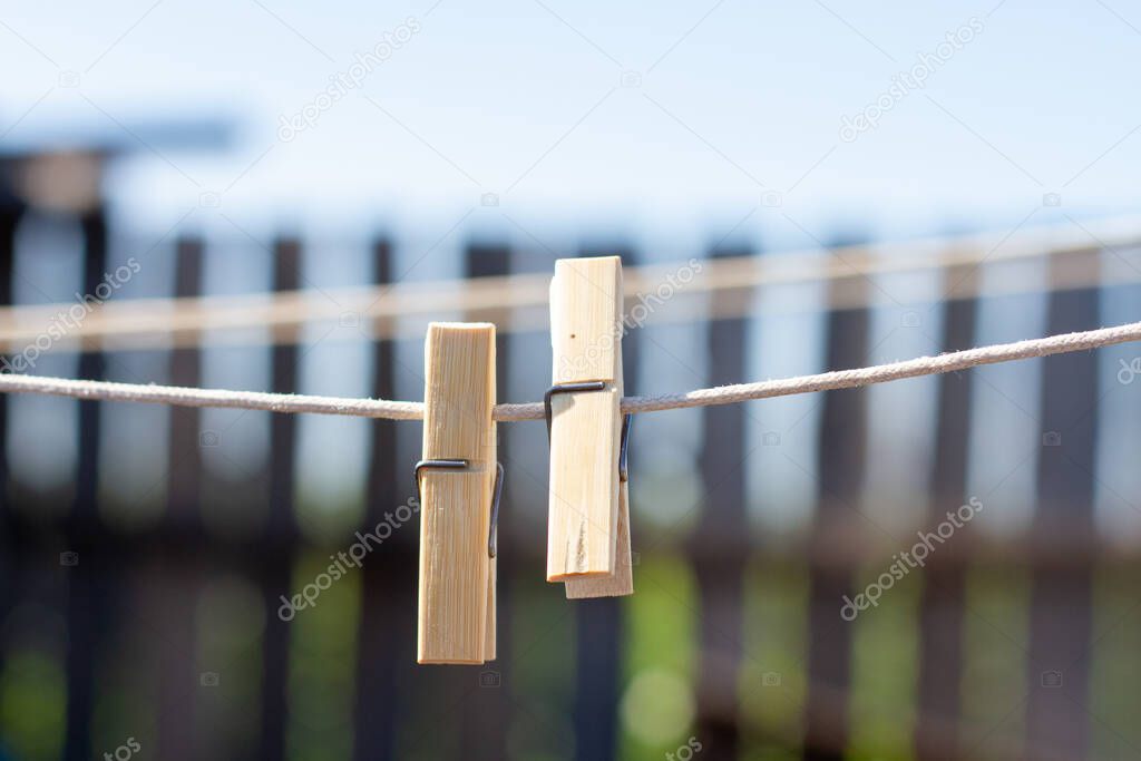 Wooden clothespins on a clothesline on the background of a wooden fence.