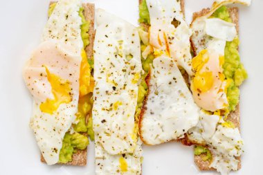 Beyaz tabakta avokado ve haşlanmış yumurtalı sandviç. Sağlıklı vejetaryen tostu. Vejetaryen yemeği..