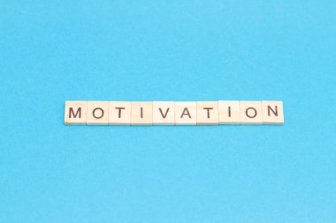 Mavi arka plandaki tahta bloklardan motivasyon kelimesi. Üst Manzara. İlham konsepti. Hedeflerin başarıları.