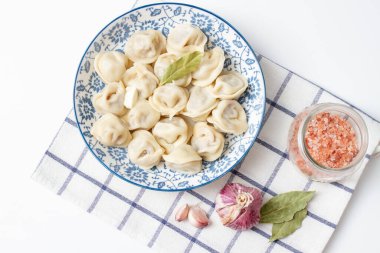 Damalı havlunun üzerinde mavi bir tabakta hamur tatlısı. Etli Ravioli..