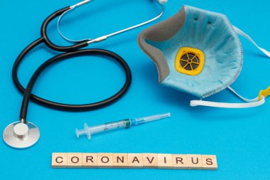CORONAVIRUS sözcüğü sanayi solunum cihazı, stetoskop ve şırınga ile mavi üzerine ahşap küplerden yapılmıştır.