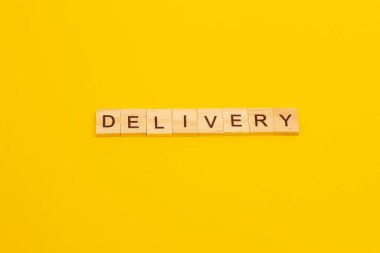 Kelime DELIVERY sarı arka planda tahta küplerden yapılır.