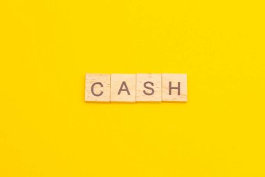 Kelime CASH sarı arka plandaki tahta küplerden yapılmış. İş konsepti