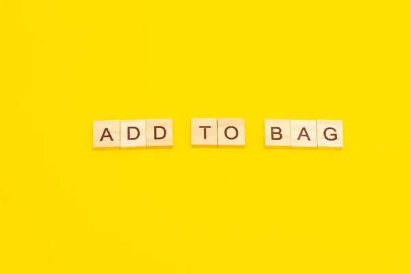 Word ADD TO BAG aus Holzwürfeln auf gelbem Hintergrund — Stockfoto