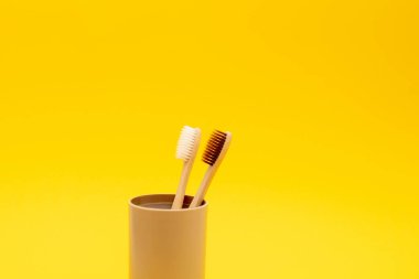 Sarı arka planda cam kaplı çevre dostu bambu diş fırçaları. Sıfır atık ve çevre dostu.