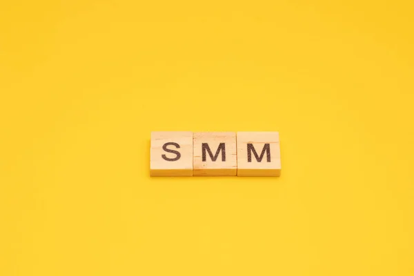 Слово SMM зроблено з дерев'яних кубиків на жовтому фоні — стокове фото