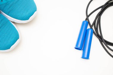 Mavi spor ayakkabılar ve mavi atlama halatı ile düz yatıyordu. Spor aletleri. Metin için boş alan