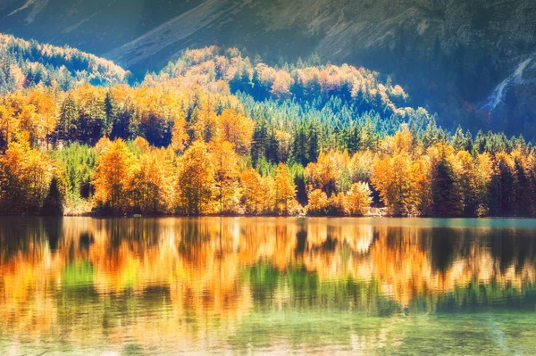 Colorful autumn trees and their reflections on the lake in Alps mountains, Austria.