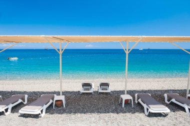 Şezlong Kemer, Türkiye'de çakıl sahilde çadır altında.