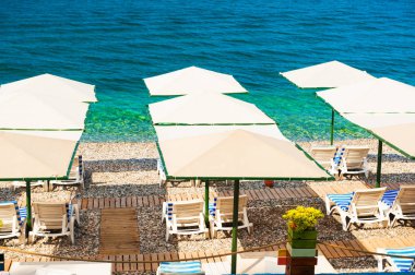 Şezlong ve plaj şemsiyeleri sahilde Kemer, Türkiye'de. Seyahat ve tatil