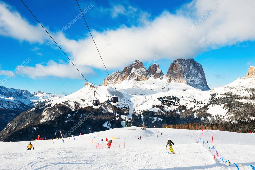 Skiers skiing down the slope in ski resort in winter Dolomite Alps. Val Di Fassa, Italy. 