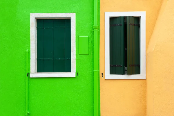 Okna z zielonymi okiennicami na żółtej i zielonej ścianie. — Zdjęcie stockowe