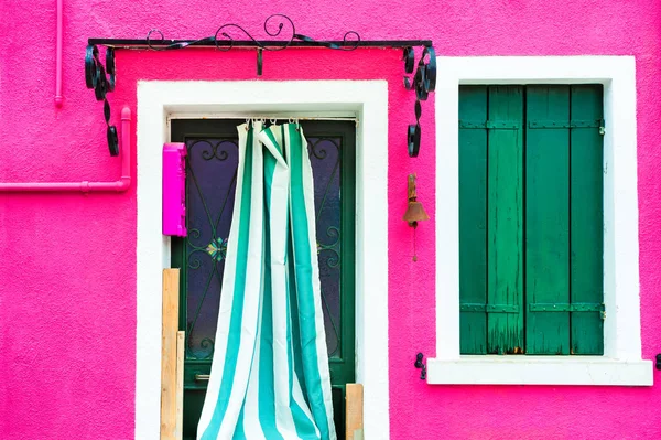 Окно с зелеными ставнями и дверью на розовой стене . — стоковое фото