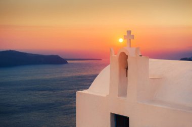 Yunanistan 'ın Santorini adasında güzel bir gün batımı. Deniz manzaralı beyaz kilise. Meşhur seyahat yeri
