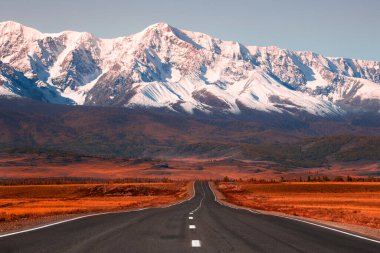 Sonbahar dağlarında güzel bir yol. Chuysky yolu ve Altai, Sibirya, Rusya 'daki Kuzey Chuya dağ sırtı manzarası. Karla kaplı dağ tepeleri ve sarı sonbahar ormanı