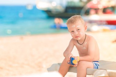 Sevimli küçük çocuk kumsalda Güneş Losyonu Şişe tutan güneş kremi ile