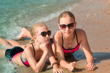 Mutlu genç kızlar güneşlenme, eğleniyor deniz kenarında