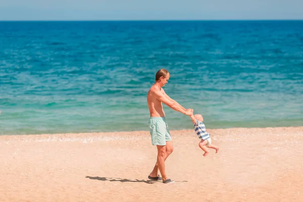 ビーチで彼の赤ちゃんと遊ぶ若い幸せな父 赤ちゃんの周りを回して — ストック写真