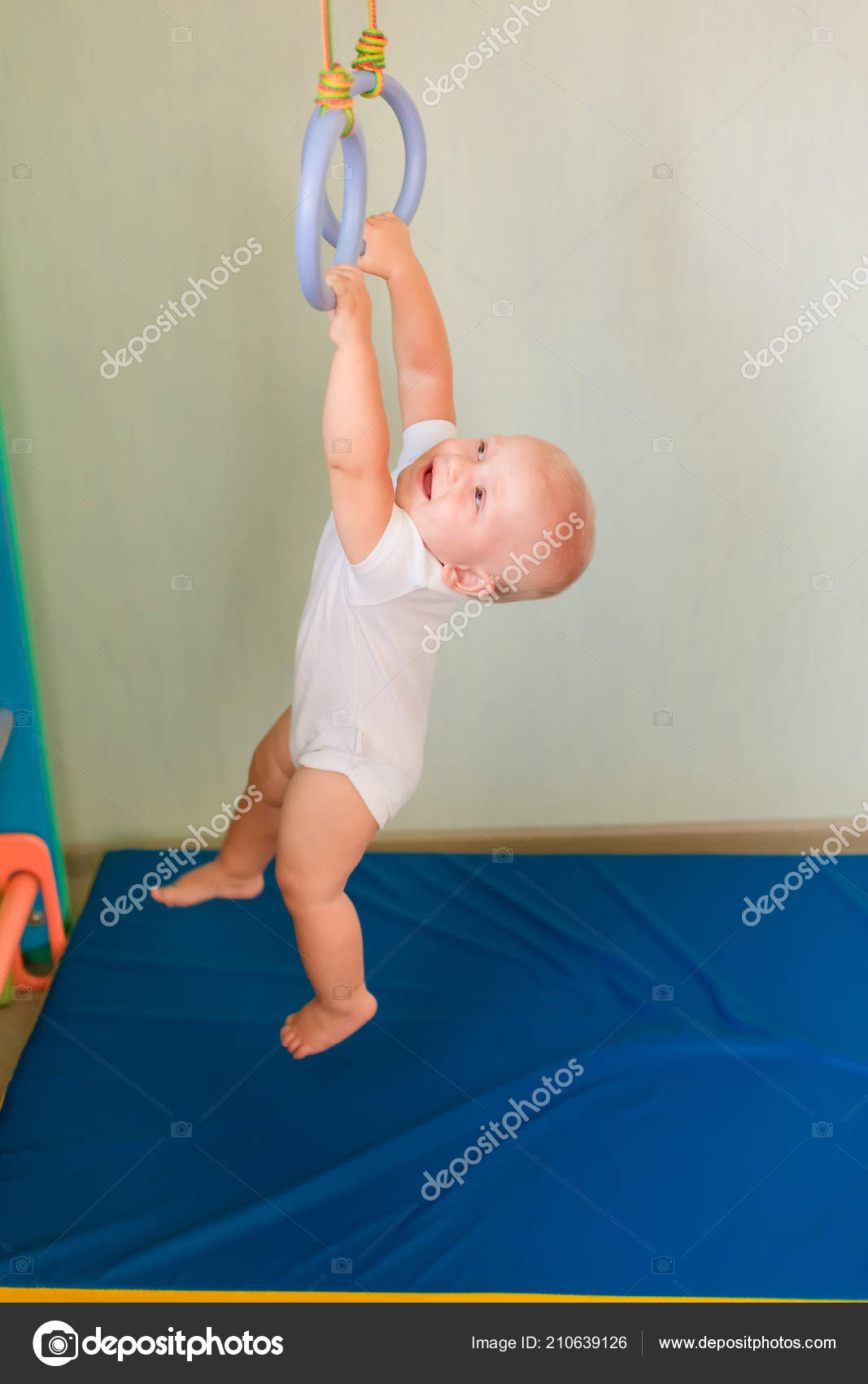 Low angle view of a pair of wooden gymnastic rings hanging on adjustable  straps from wooden beams in the ceiling of a gym stock photo - OFFSET