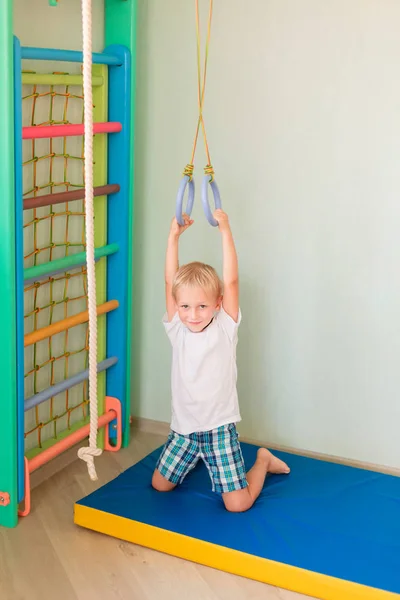 幸せな小さな男の子の家の壁のジムのリングに掛かっています 子供のスポーツの開発コンセプト — ストック写真