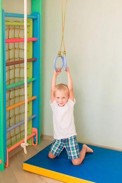 幸せな小さな男の子の家の壁のジムのリングに掛かっています 子供のスポーツの開発コンセプト — ストック写真