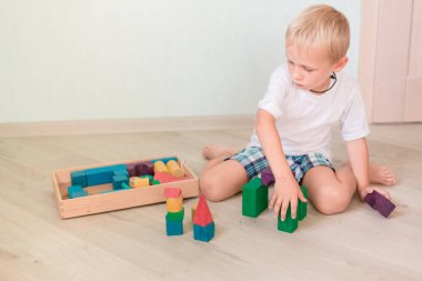 Sevimli küçük çocuk odasında renkli tahta bloklarla oynama. Erken geliştirme kavramı