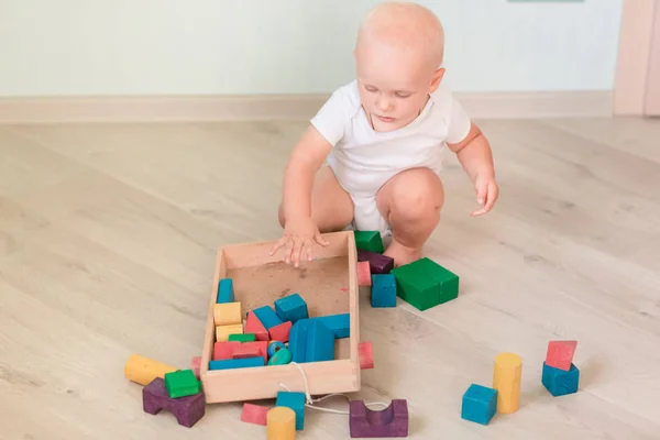 部屋に色の木製ブロックで遊ぶかわいい赤ちゃん 初期の開発コンセプト — ストック写真
