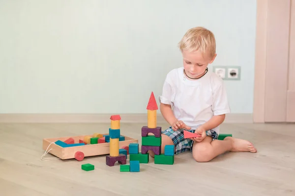 部屋に色の木製ブロックで遊ぶかわいい男の子 初期の開発コンセプト — ストック写真