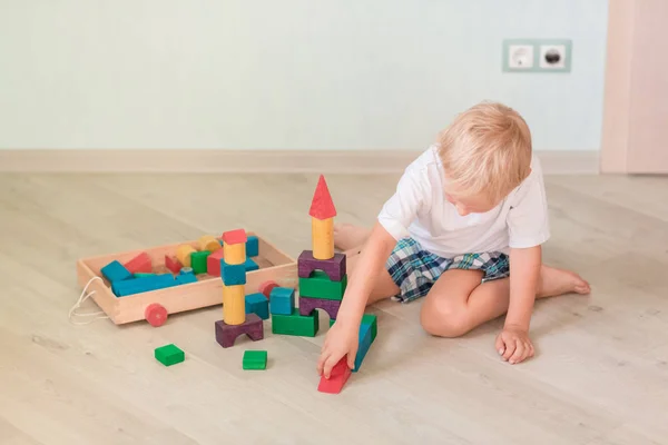 部屋に色の木製ブロックで遊ぶかわいい男の子 初期の開発コンセプト — ストック写真