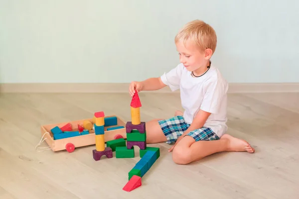 部屋に色の木製ブロックで遊ぶかわいい男の子 初期の開発コンセプト — ストック写真