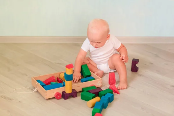 部屋に色の木製ブロックで遊ぶかわいい赤ちゃん 初期の開発コンセプト — ストック写真