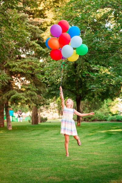 ヘリウムの大きな花束を抱えて遊んで幸せな女の子いっぱい公園で色とりどりの風船 — ストック写真