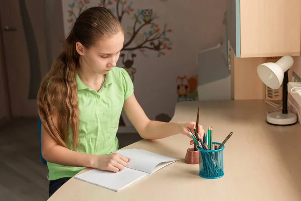 かわいい女の子のテーブルで宿題を書く左利き — ストック写真