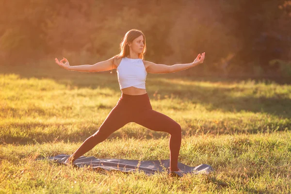 Beautiful young woman practicing yoga in the park — Stock Photo, Image