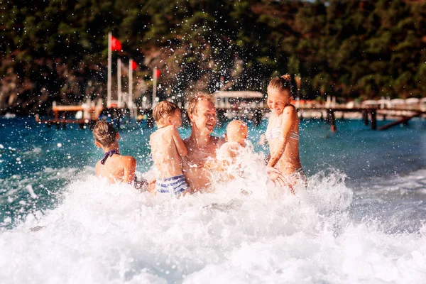 Glückliche Kinder mit seinem Vater am Strand Spaß haben — Stockfoto