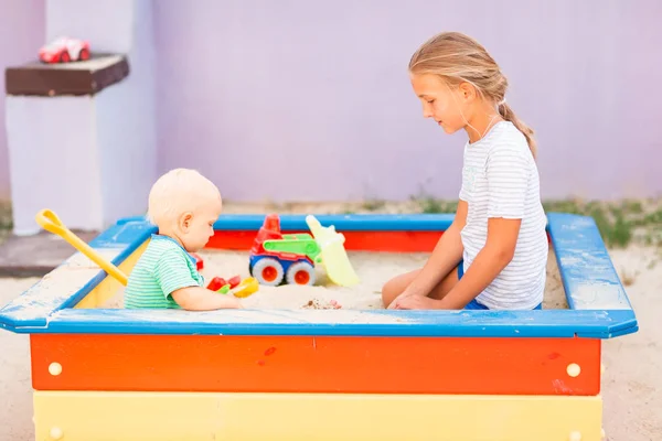 Schattige baby jongen spelen met zijn zus in de sandbox — Stockfoto