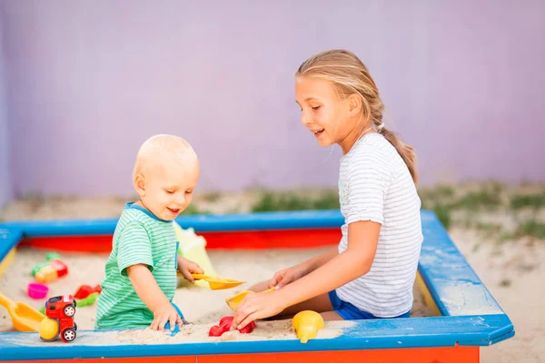 Schattige baby jongen spelen met zijn zus in de sandbox — Stockfoto