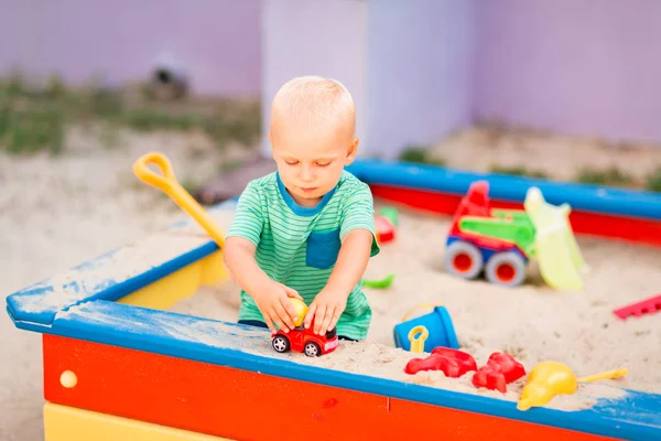 Bonito menino brincando na caixa de areia — Fotografia de Stock
