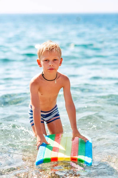 Feliz niño jugando en las olas en la playa — Foto de Stock