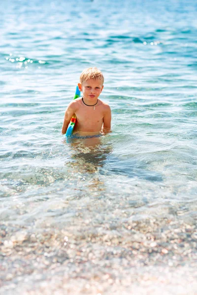 Glücklicher kleiner Junge, der in den Wellen am Meer spielt — Stockfoto