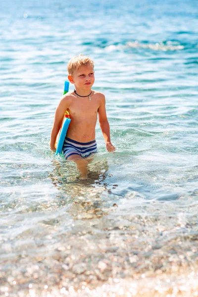 Gelukkige kleine jongen spelen in de golven aan de kust — Stockfoto