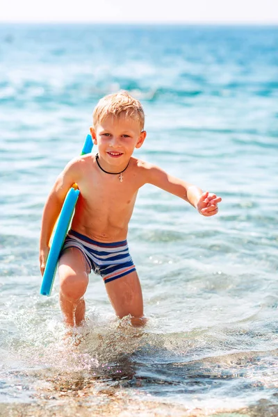 Feliz niño jugando en las olas en la playa — Foto de Stock