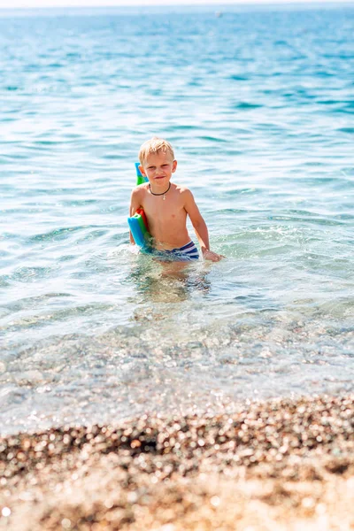 Gelukkige kleine jongen spelen in de golven aan de kust — Stockfoto