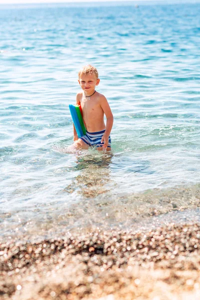 Feliz niño jugando en las olas en la playa —  Fotos de Stock