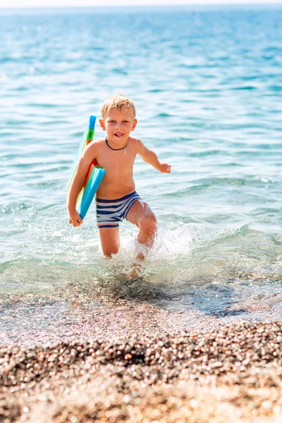 Szczęśliwy mały chłopiec grając w fale nad morzem — Zdjęcie stockowe