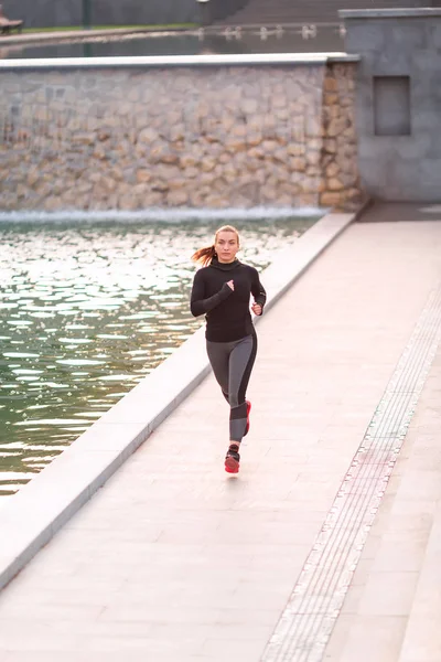 Schöne junge sportliche Frau joggt im Park — Stockfoto